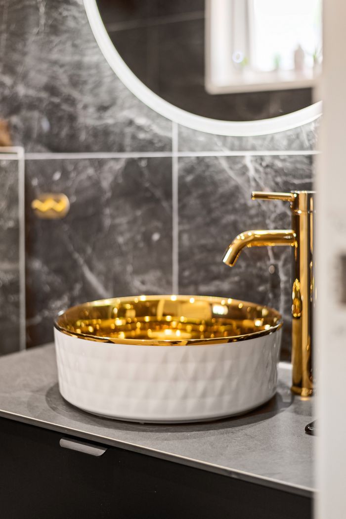 Luxury bathroom interior with a golden sink and modern faucet, offering an elegant and sophisticated design.