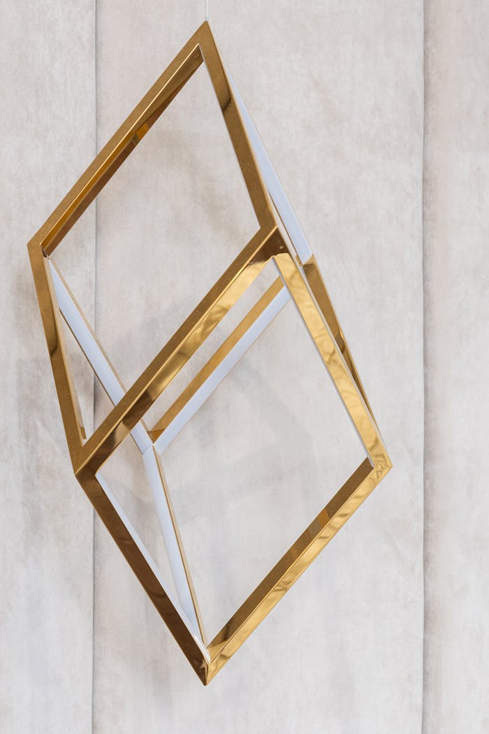 The Art of Drawing Readers In: Your attractive post title goes here Golden metal geometric cube shaped decor hanging on gray wall in modern apartment
